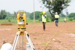 A team of survey engineers working with a theodolite at a commercial building construction site. A team of survey engineers working with a theodolite at a commercial building construction site.