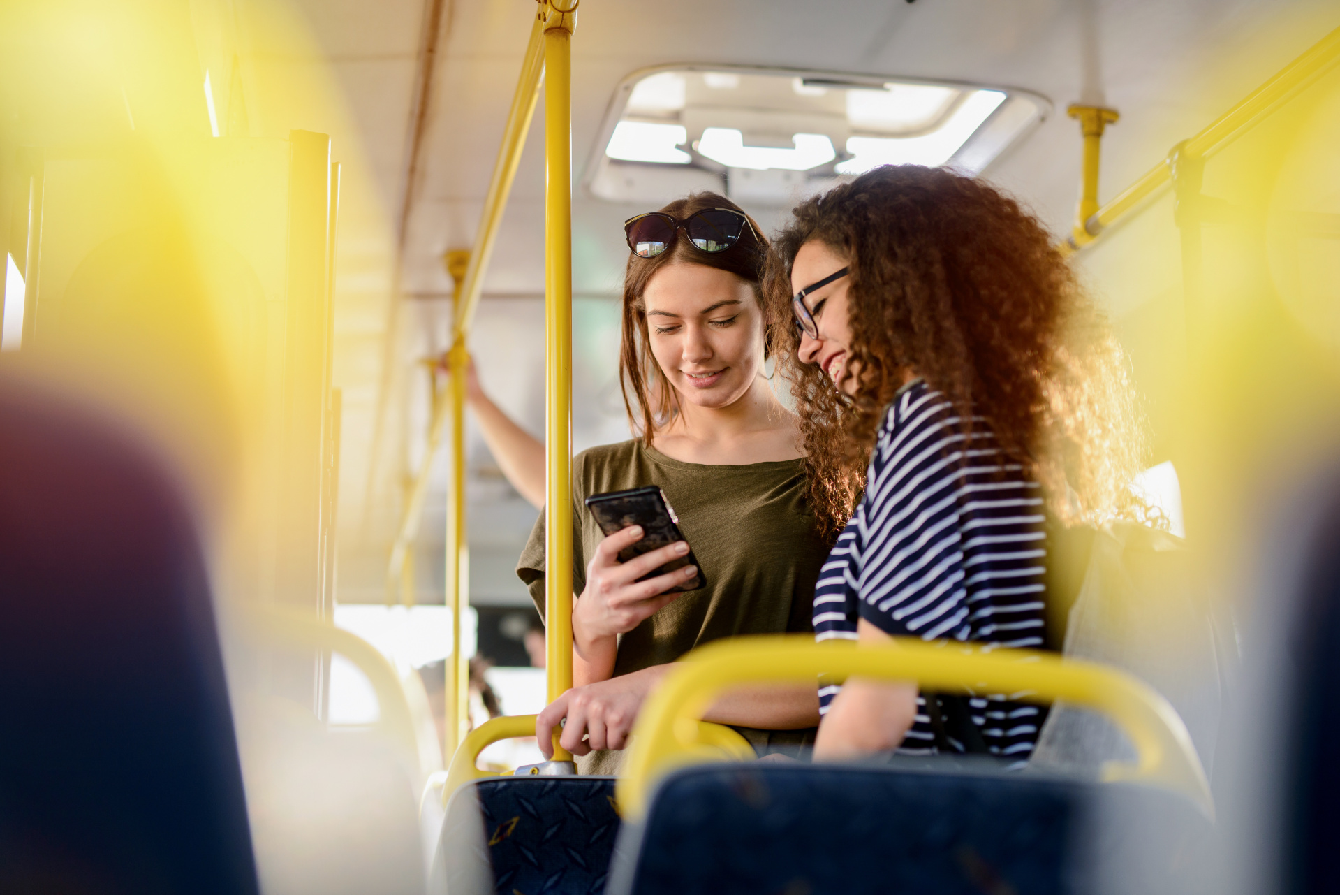 Zwei Freundinnen stehen im Bus und unterhalten sich.