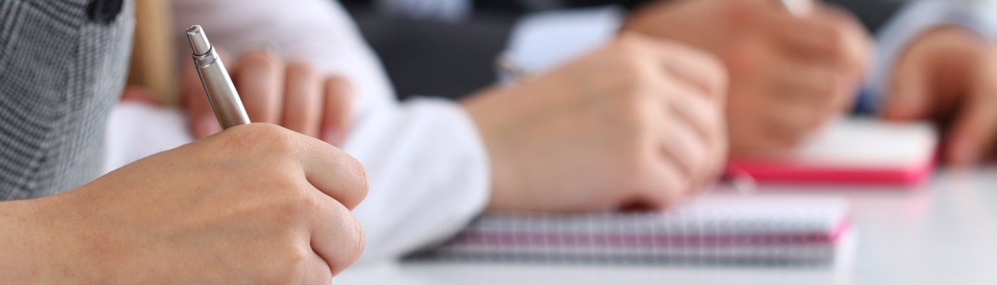 Close up view of students or businesspeople hands writing someth