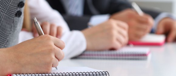 Close up view of students or businesspeople hands writing someth