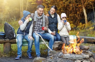 happy family sitting on bench at camp fire