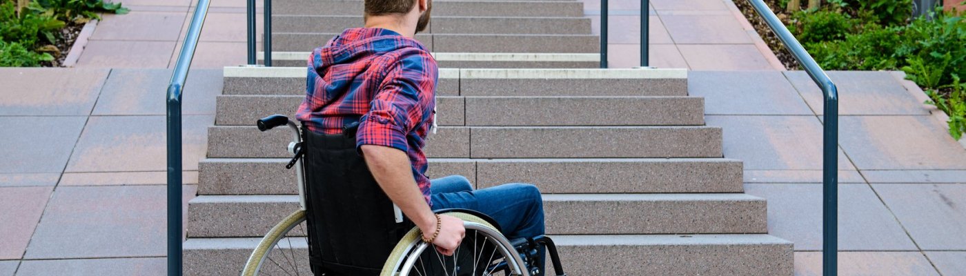 disabled man in wheelchair in front of stairs
