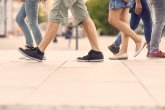 Auf dem Bild ist der untere Teil (Beine und Füße) von Personen beim Gehen zu sehen.