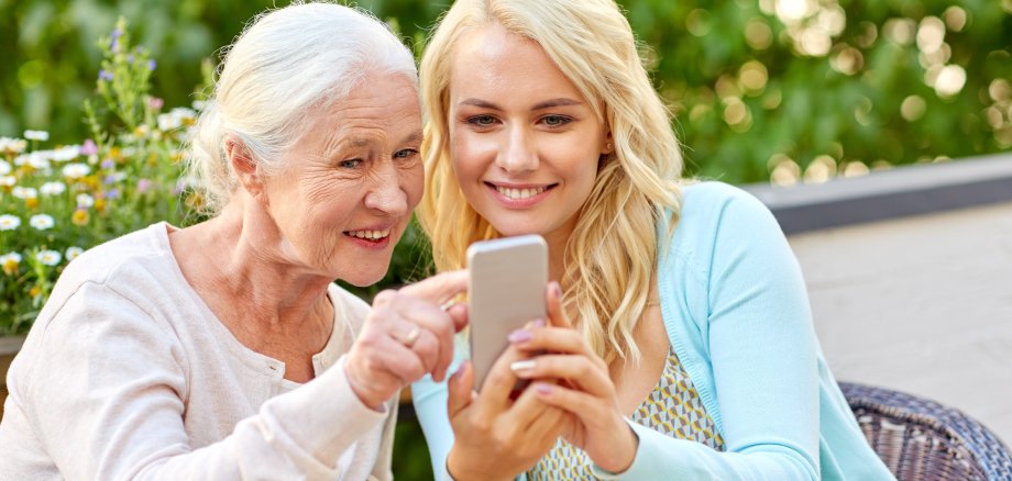 daughter and senior mother with smartphone at cafe