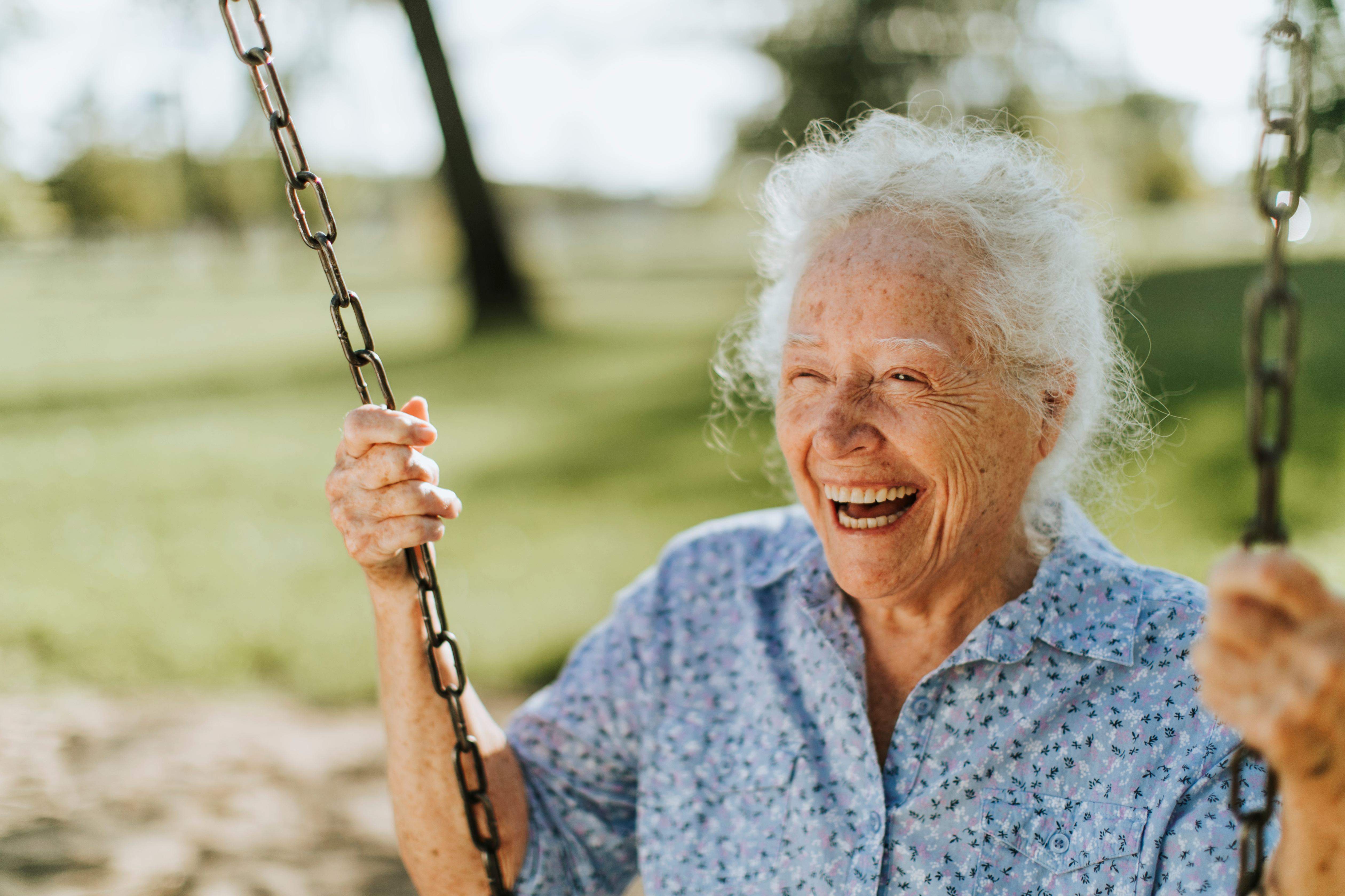 Cheerful senior woman on a swing at a playground Cheerful senior woman on a swing at a playground