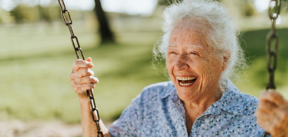 Fröhliche ältere Dame auf einer Schaukel