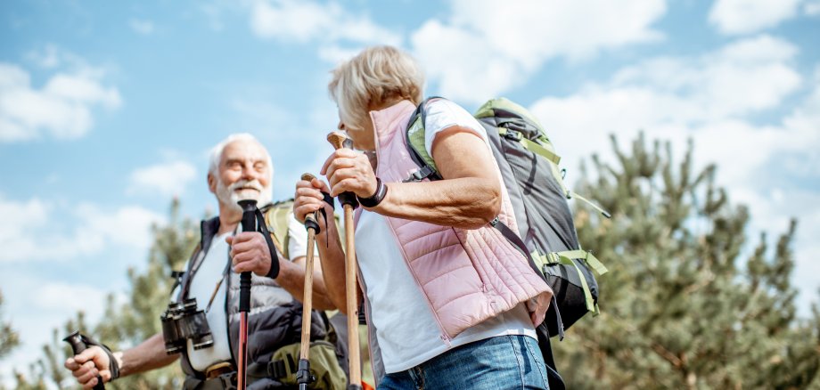 Zwei fröhliche, ältere Personen wandern