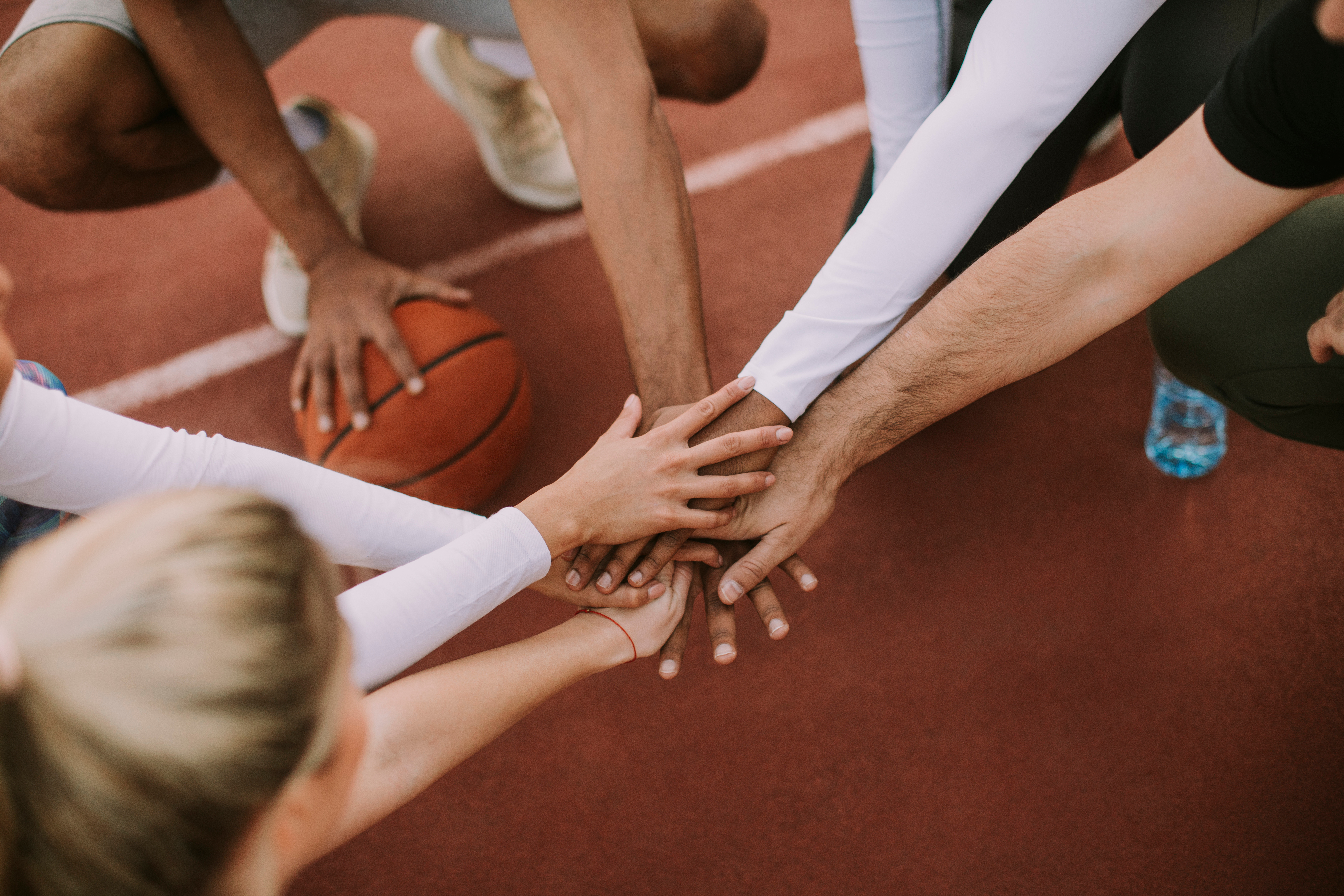 Top view of basketball team holding hands over court