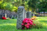 Reihe von Grabsteinen mit Blumen auf einem Friedhof