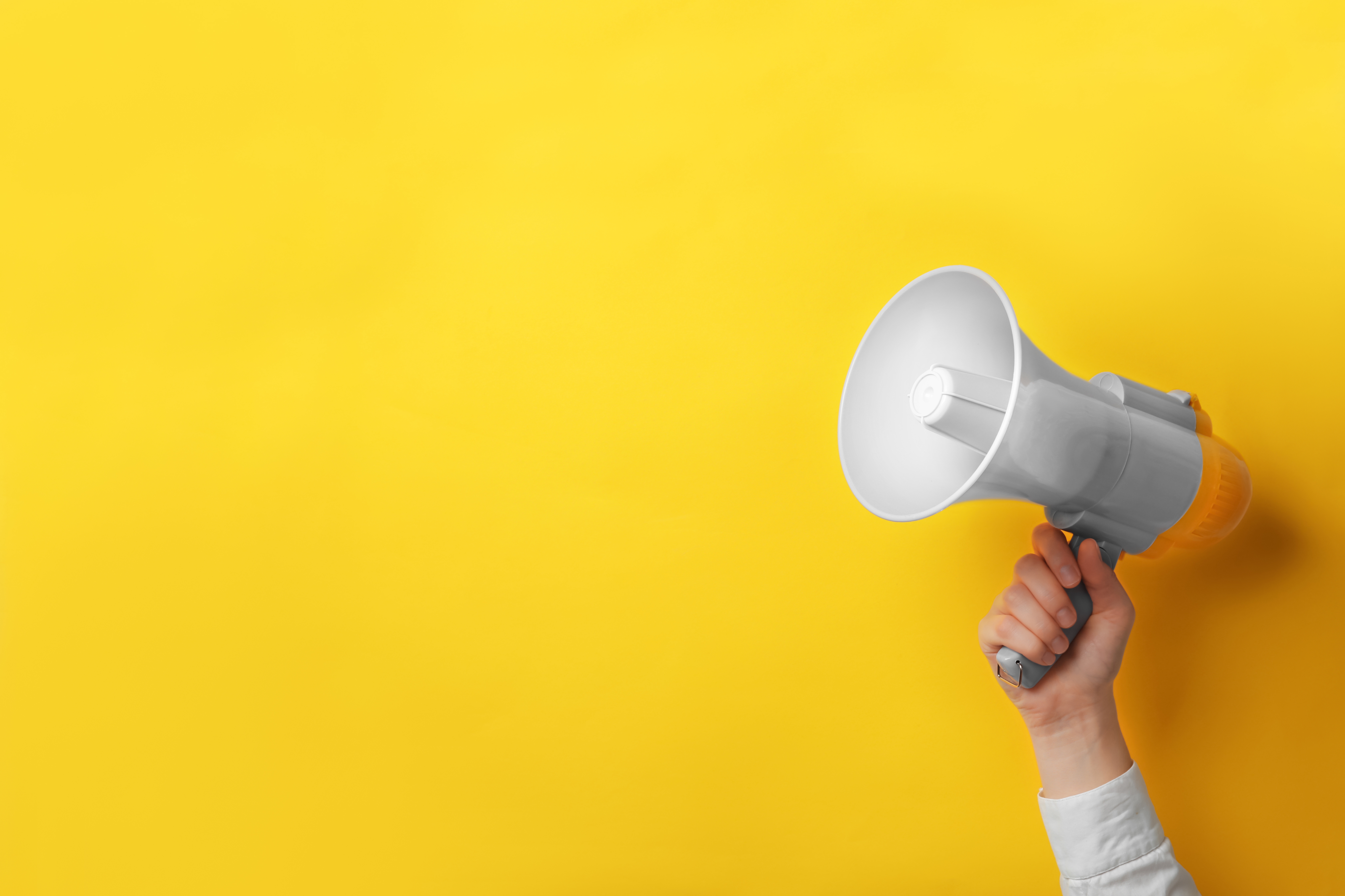 Mann hält Megaphon vor gelben Hintergrund