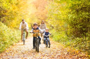 Young family in warm clothes cycling in autumn park Young family in warm clothes cycling in autumn park