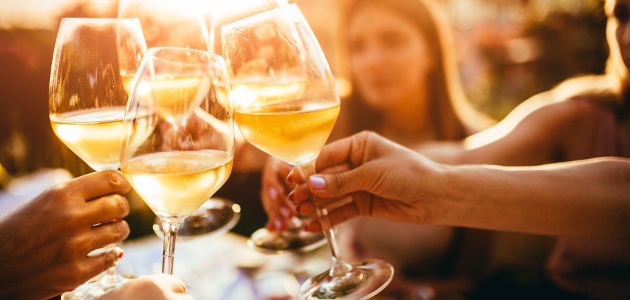 Menschen stoßen mit Wein auf der Sommerterrasse eines Cafés an