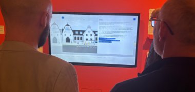 Besuchende der Ausstellung betrachten einen Bildschirm mit der Mobilitätsberatung