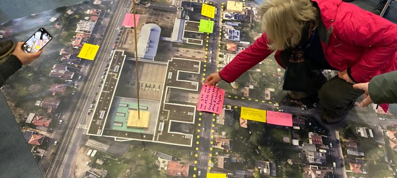Das Bild zeigt einen Teppich mit dem Luftbild der Zepplinstraße aufgedruckt. Personen haben Anmerkungen auf Klebezettel geschrieben und an die entsprechenden Stellen aufgeklebt.