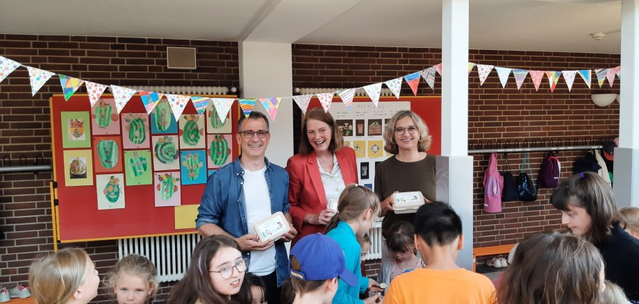 Alan Moss, Antje Runge und Andrea Königslehner verteilen die beliebten Stadtwerke Oberursel-Snackboxen an die Erstklässlerinnen und Erstklässler der Grundschule Weißkirchen.