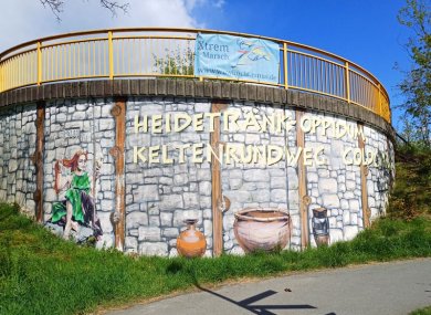 Bemalter Brückenpfeiler am Aufgang zum Heidetränk Oppidum. Zu sehen ist eine keltische Mauer, ein Kessel und eine keltische Frau