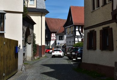 Gleicher Blick in die Hospitalstrasse wie auf der alten Fotografie. Manche Häuser stehen nicht mehr. Man sieht Autos anstatt Schafe