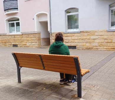 Eine Person sitzt auf der neuen Bank in der Kumeliusstraße