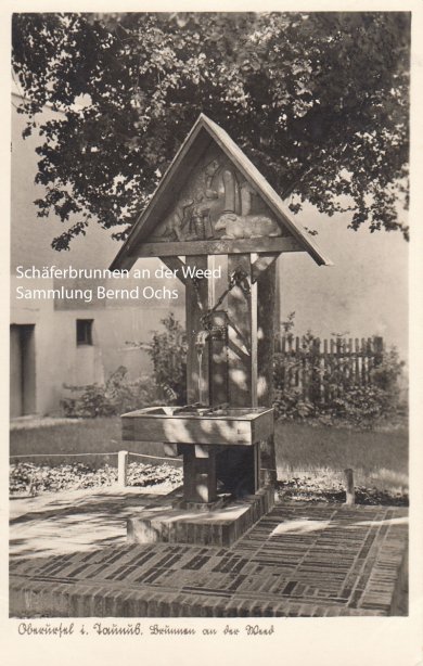 Ein alter Brunnen steht in einem Hof vor einem Baum