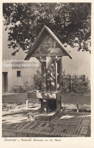 Ein alter Brunnen steht in einem Hof vor einem Baum
